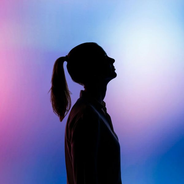 Silhouette of a person in a powerful yoga pose against a mint-colored background.